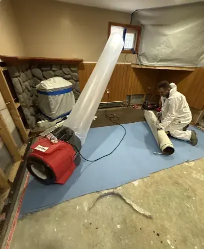 Technician setting up plastic containment and a dehumidifier in an emptied room