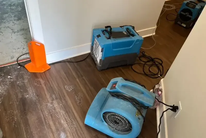 Air movers and a dehumidifier drying a room after a leak