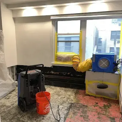 Dehumidifier and air mover drying a room with flooring removed