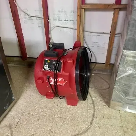 Red air mover drying an opened wall behind plastic, as Seminole jobs use