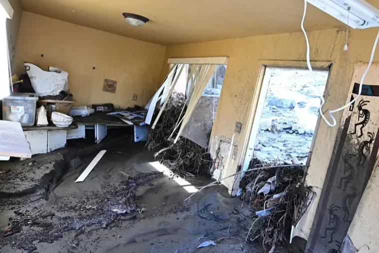 Mud and storm debris pushed through broken doors into a flooded home