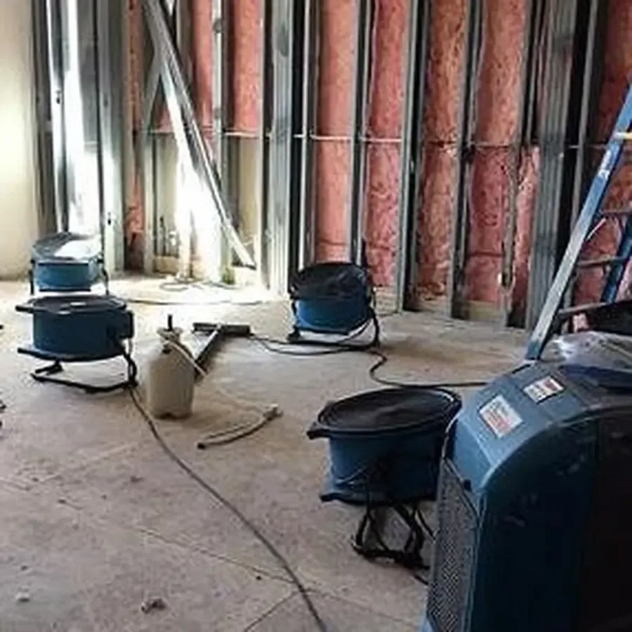 Air movers and a dehumidifier drying opened wall framing